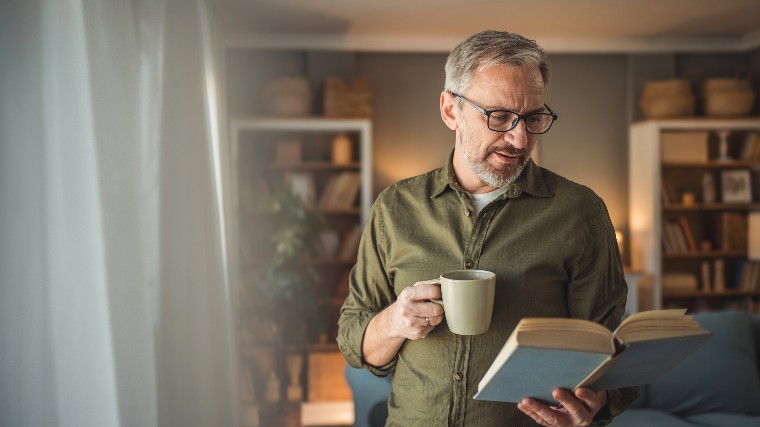 Man drinking coffee and reading book.