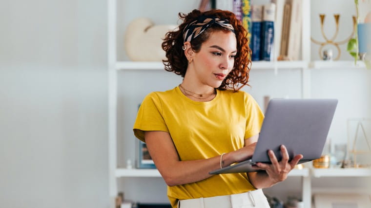 Young woman standing while using laptop.