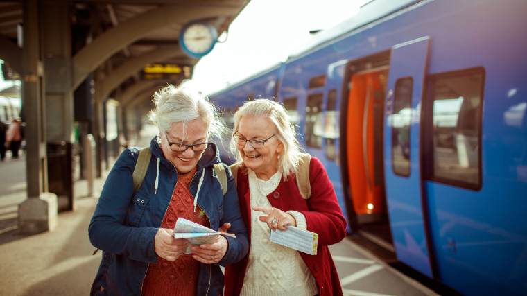 Two seniors checking their map outside a train station.