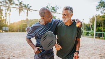 Two retirement age men playing beach tennis.