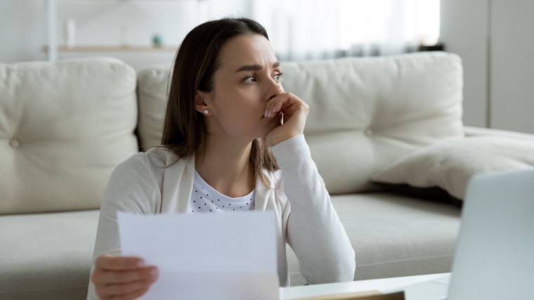 Worried woman holding loan rejection letter.