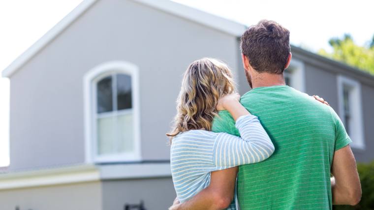 young couple looking at the exterior of their house