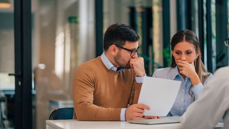 Concerned couple reviewing paperwork.