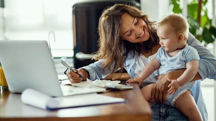 Mother managing finances while taking care of small baby.