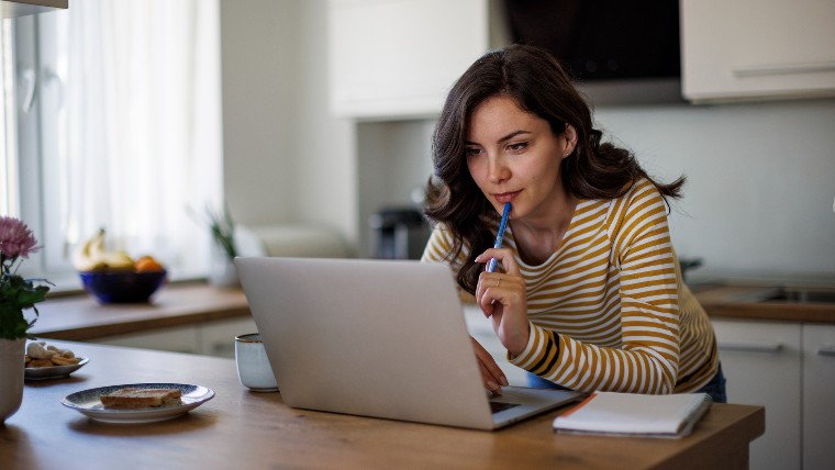 Woman doing research with her laptop while taking notes.