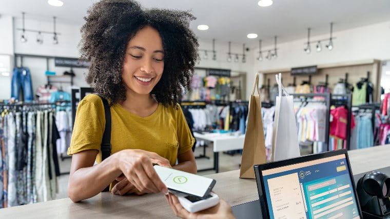 Young woman using her phone to make a payment at a checkout.
