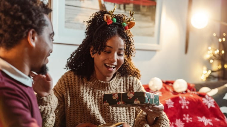Excited young woman opening a Christmas present.