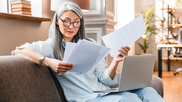 Woman reading paperwork on her couch.