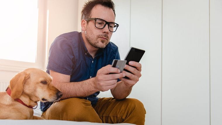 Man using phone and holding credit card.