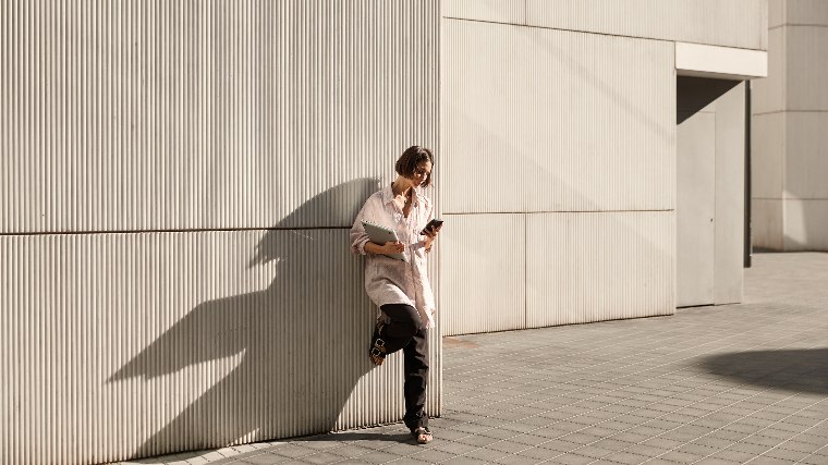 Woman standing outside and checking her phone.