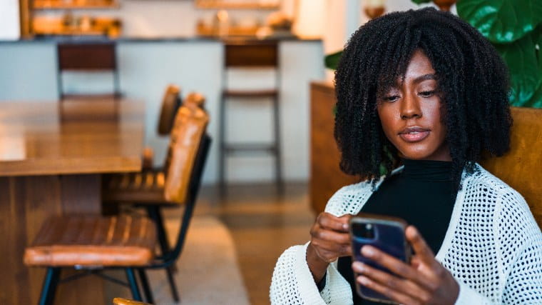 Young woman in coffee shop checks her phone.