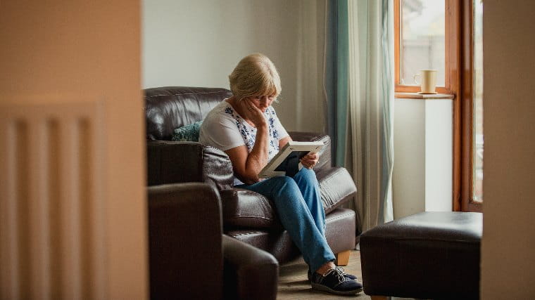 Mournful elderly woman looking at framed photo.