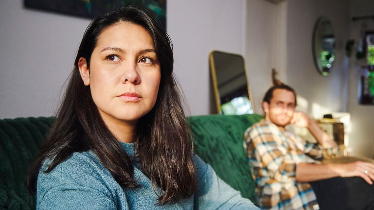 Unhappy couple sitting on couch together.