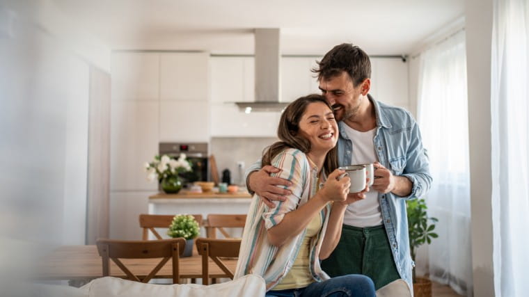 Young couple drinking coffee together in living room.