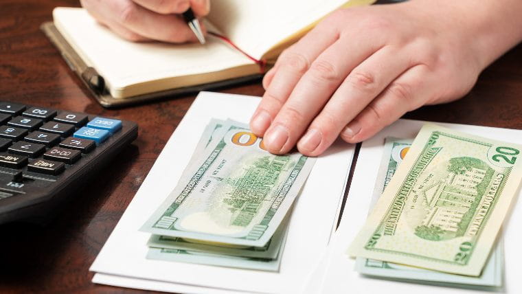 Two piles of cash on top of envelopes.