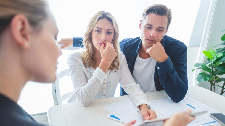 Concerned couple talking with real estate agent.