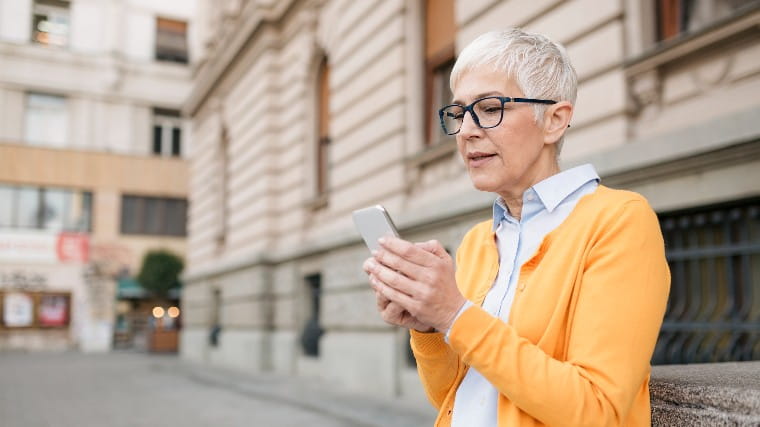 Senior woman reads phone with look of concern.