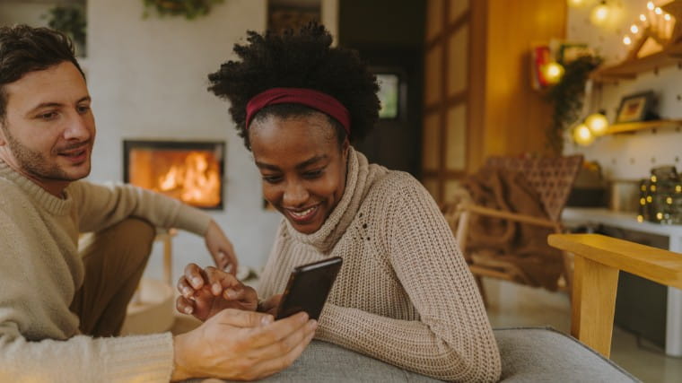 Couple looking at phone together during holiday season.