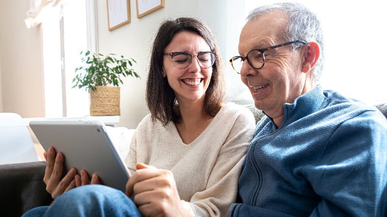 Adult daughter sitting and laughing with elderly father.