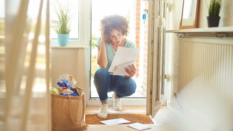 Woman crouching in doorway reading letter.