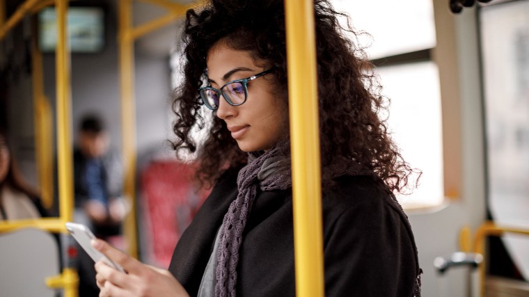 Young woman checking phone while riding train.