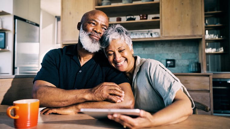 Senior couple sitting together at a table and smiling.