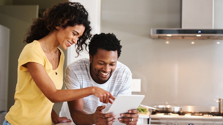 Young couple reading good news on a tablet.