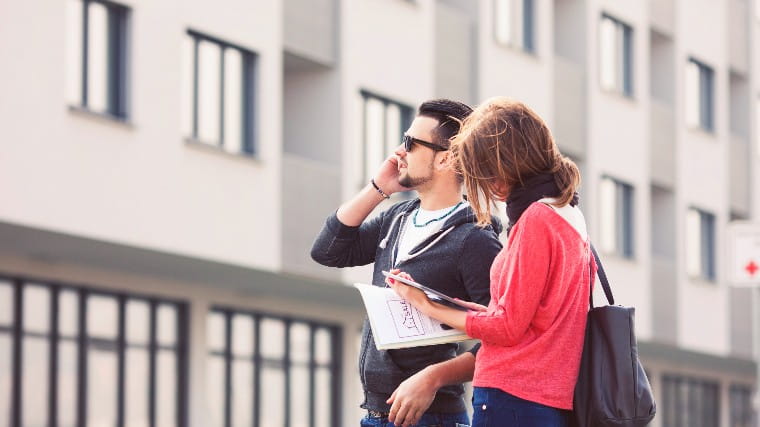 Couple walking down street looking at apartments.
