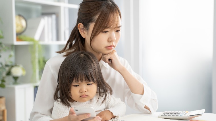 Mother holding child while reviewing finances.