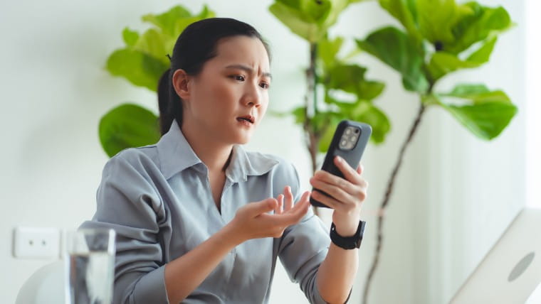 Concerned woman reading bad news on phone.