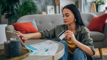 Woman holding credit card and reading bills.