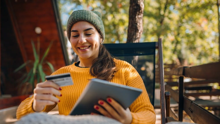 Young woman holding tablet and looking at credit card.