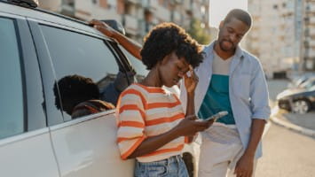 Young couple standing outside of their car.