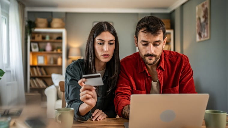 Couple using laptop and holding credit card.