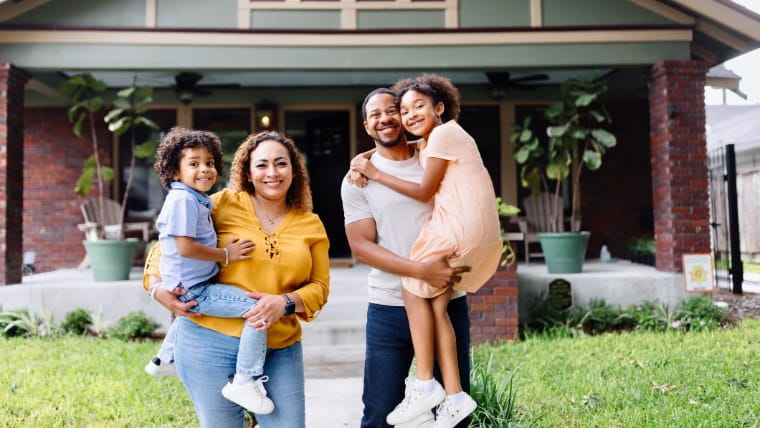 Happy family standing outside their new home.