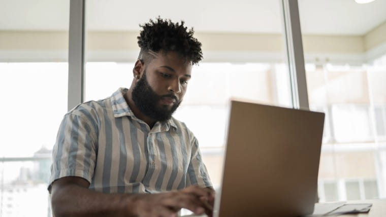 Young man working at laptop computer.