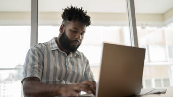 Young man working at laptop computer.