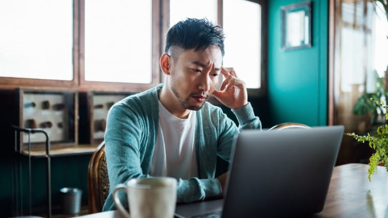 Concerned man looking at laptop.