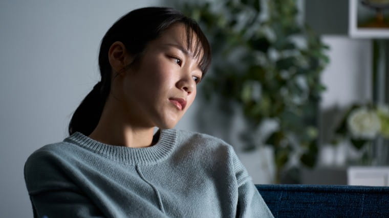 Sad young woman sitting in dimly lit room.