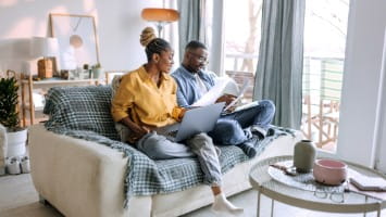 Couple sitting on couch reviewing finances together.