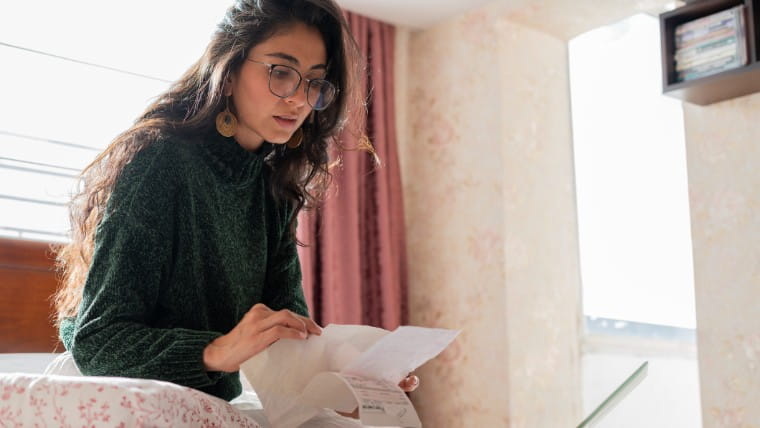 Young woman looking over her bills.