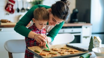 Mother helping young son decorated Christmas cookies.