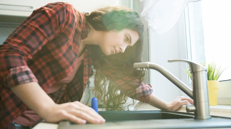 Young woman examining her faucet.