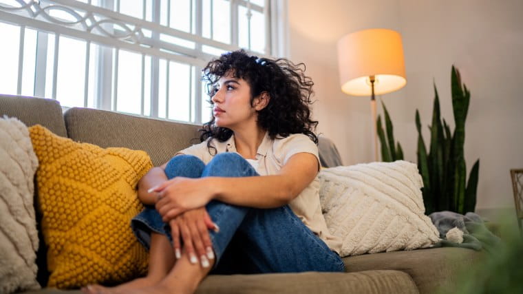Worried young woman sitting on couch.