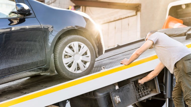 Tow truck driver loading a vehicle for repossession.