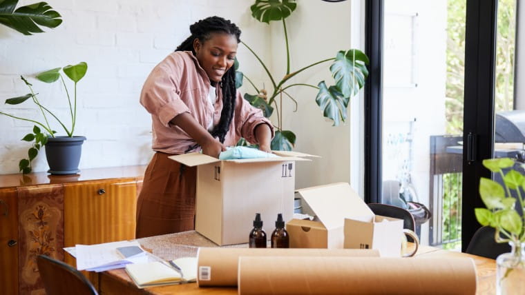 Young businesswoman packing box for shipping.