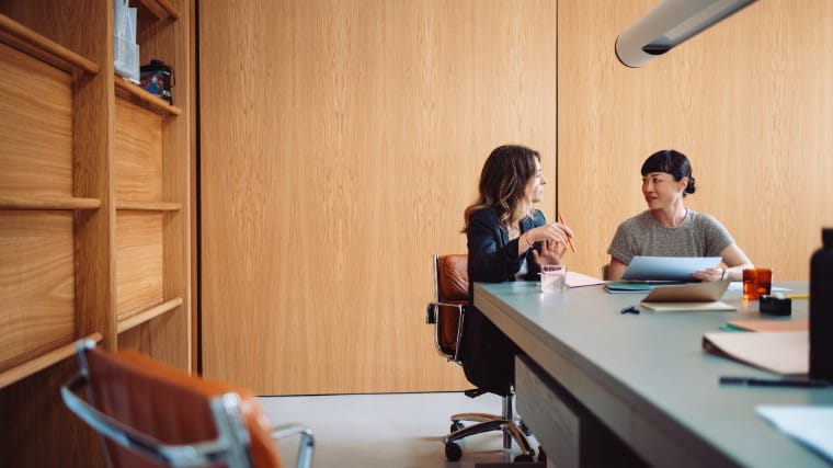 Two women working together in a meeting room.