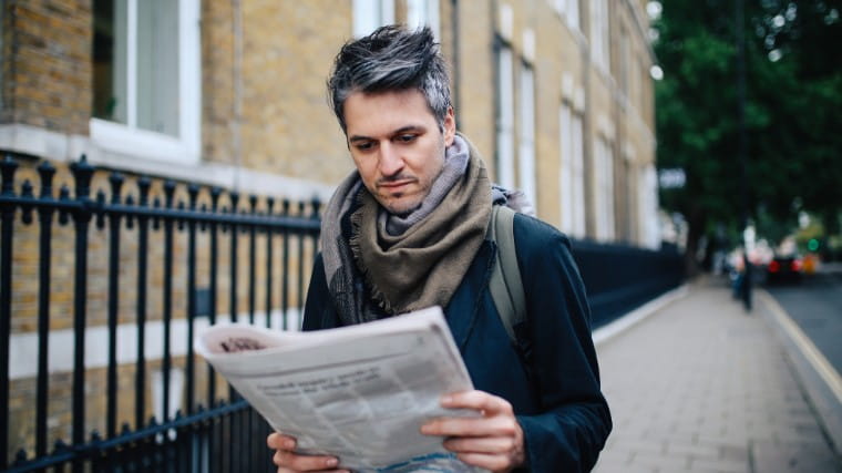 Man walking and reading newspaper.