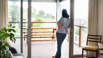 Woman looking out window of home.
