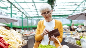 Woman looking in wallet while in grocery store.